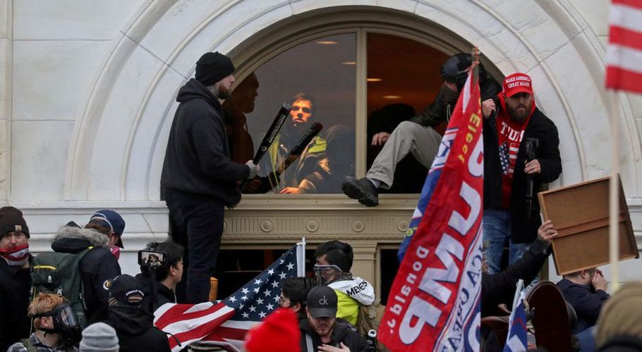A mob of supporters of Donald Trump climbs through a window as they storm the US Capitol Building in Washington. Source: Reuters