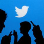 People holding mobile phones are silhouetted against a backdrop projected with the Twitter logo. Source: Reuters.