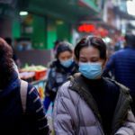 People wearing face masks walk on a street market following an outbreak of Covid-19 in Wuhan. Source: Reuters.