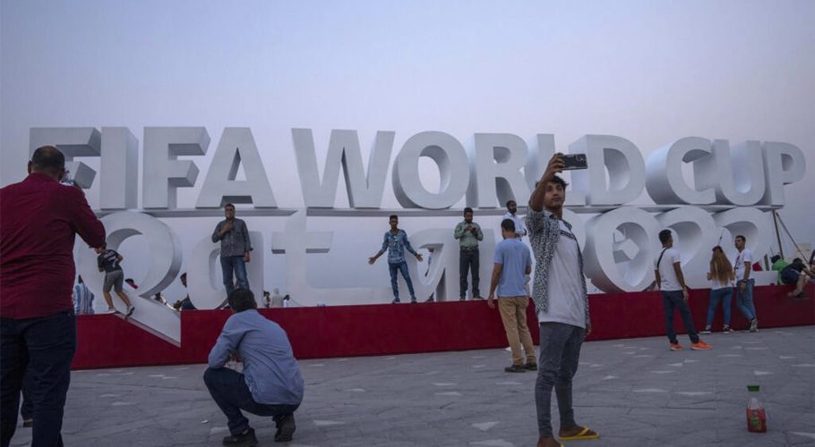 People take photographs in front of a FIFA World Cup sign on Doha's corniche on October 21, 2022. © Nariman El-Mofty, AP