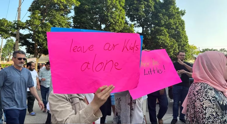 People at a protest in Windsor, Ont., on June 20, 2023 hold signs saying 'Leave Our Kids Alone,' in regards to the local school board's gender identity policy. (Jennifer La Grassa/CBC)