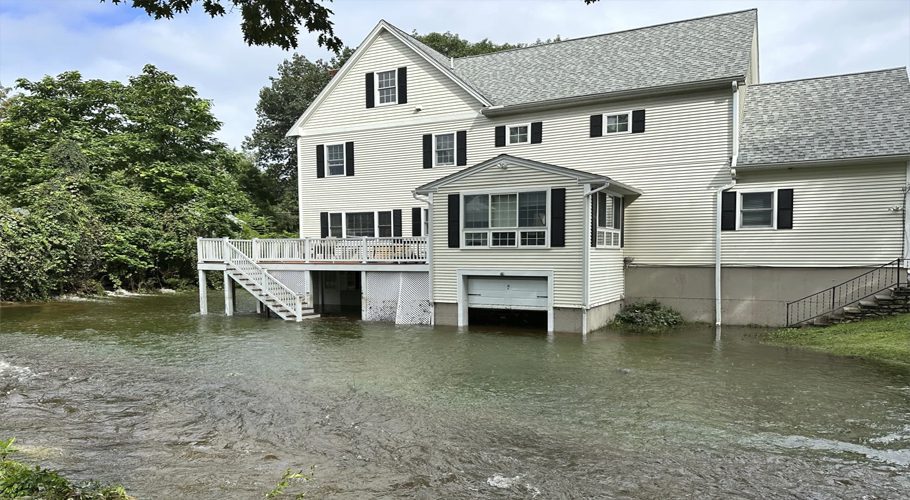 A brook in Leominster, Mass. overflows into the garage of a home following heavy rains overnight, Tuesday, Sept. 12, 2023. (AP Photo/Michael Casey)