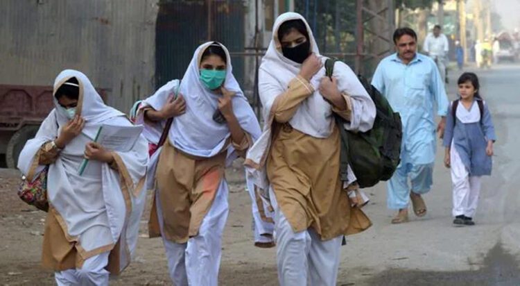 Students wearing facemasks walk through a street to their school in Peshawar. (File/AFP)