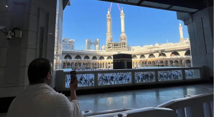 A Muslim man uses a mobile phone during Umrah, at the Grand Mosque, while construction cranes are seen in the background, in the holy city of Mecca, Saudi Arabia, December 18, 2023. (Reuters)