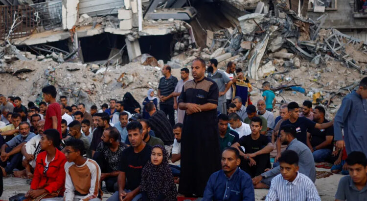 Palestinians hold Eid al-Adha prayers by the ruins of ar-Rahma Mosque destroyed by Israeli air strikes, in Khan Younis, in the southern Gaza Strip. [Mohammed Salem/Reuters]