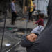 A Palestinian woman holds a child, as Palestinians inspect the damage at a school sheltering displaced people, following an Israeli strike, in Gaza City, April 23, 2025. REUTERS/Dawoud Abu Alkas