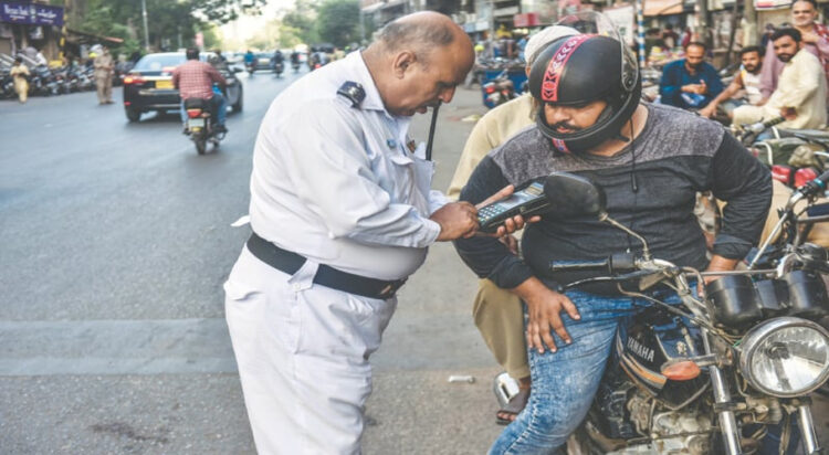 A motorcyclist is caught by a sergeant over wrong-way violation. —Fahim Siddiqi / White Star via Dawn.com