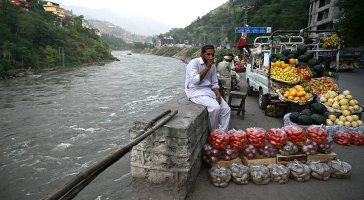 A fruit vendor sits on his stall alongside Jhelum River in Muzaffarabad.–AFP