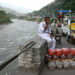 A fruit vendor sits on his stall alongside Jhelum River in Muzaffarabad.–AFP