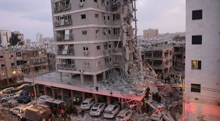People stand near a residential building that was hit following missile attack from Iran on Israel, at central Israel June 15, 2025. REUTERS/Tomer Appelbaum