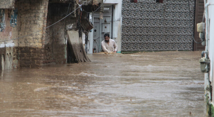 A resident navigates through a flooded street in a neighbourhood of Mingora, the main town in the Swat Valley. Photograph: Naveed Ali/AP