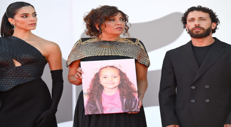 From left, Saja Kilani, Kaouther Ben Hania and Motaz Malhees display a picture of Hind Rajab as they arrive for the premiere of The Voice of Hind Rajab. Photograph: Ettore Ferrari/EPA