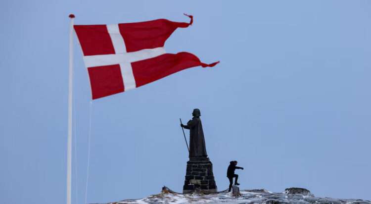 A man walks as Danish flag flutters next to Hans Egede Statue in Nuuk, Greenland, March 9, 2025. REUTERS/Marko Djurica/File Photo