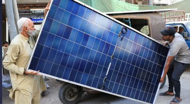 Men load solar panels on a rickshaw at a market in Karachi, Pakistan, on March 26. | REUTERS